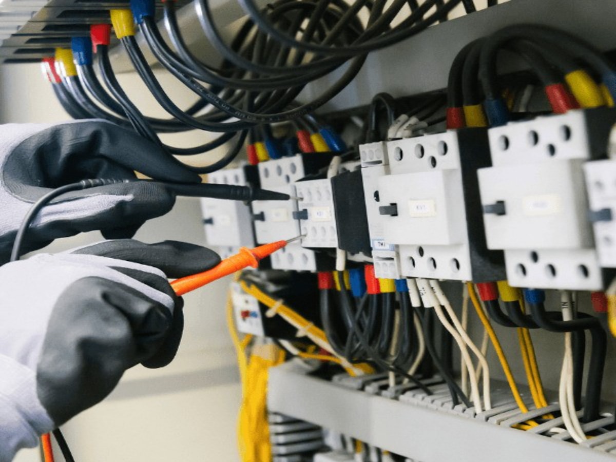 Električar pri merjenju napetosti v razdelilni omarici z multimetrom - EGH